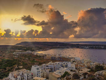 High angle view of townscape by sea against sky during sunset