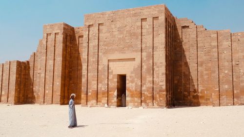 Woman standing by historical building against sky