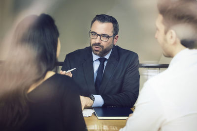 Confident mature male lawyer discussing with customers at office