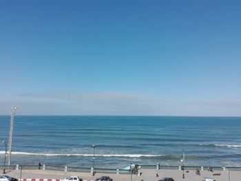 People on beach against clear blue sky