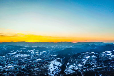 Aerial view of snowcapped mountains against sky during sunset