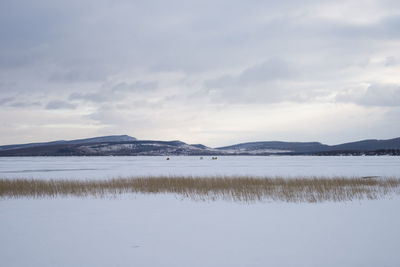 A frozen lake covered with snow, with fishermen in the distance, in the  kuznetsk alatau.