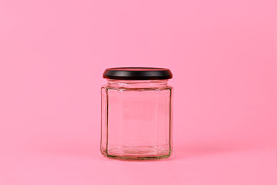 Close-up of glass jar against pink background