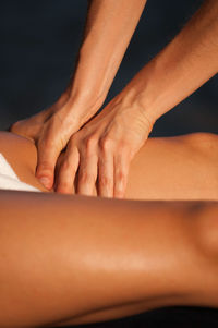 Cropped hands of masseuse giving massage on leg of woman