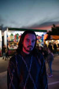 Young man with long hair in a red and purple light posing