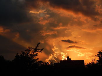 Low angle view of silhouette trees against cloudy sky