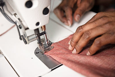 Cropped hand of tailor using sewing machine