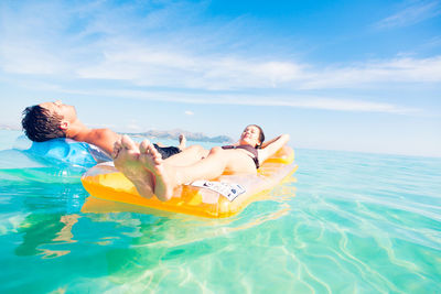 People relaxing in swimming pool against sea