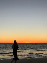 Silhouette man looking at sea against sky during sunset