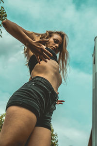 Low angle view of young woman against sky