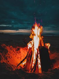 Bonfire on log against sky