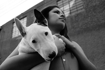 Low angle view of young woman holding bull terrier