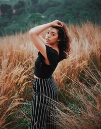 Young woman looking away while standing on field