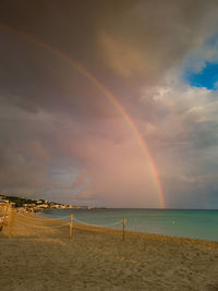 Scenic view of sea against rainbow in sky