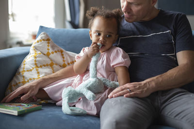 A father sits to read to his young daughter