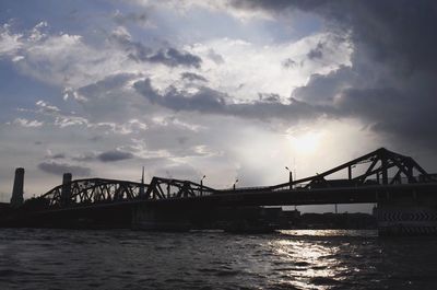 Bridge over river against cloudy sky