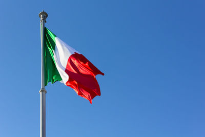 Low angle view of flag against clear blue sky