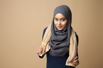 Young woman holding towel against beige background