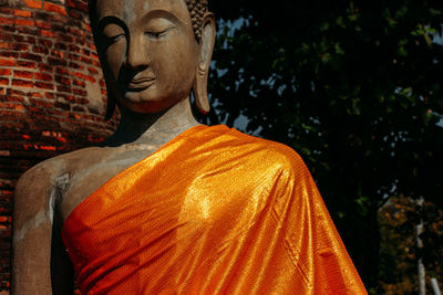 Statue of buddha against orange wall