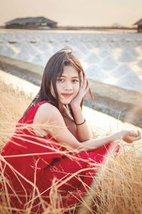 Portrait of smiling young woman sitting on land