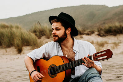 Young man playing guitar at beach