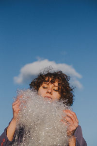 Woman looking at plastic against blue sky