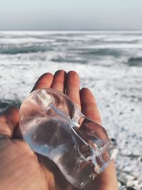 Cropped hand holding ice at beach