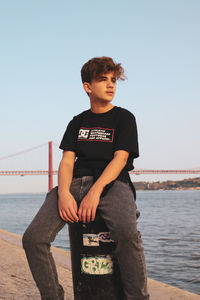 Boy standing by railing against clear sky