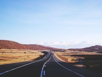 Road leading towards mountain against sky