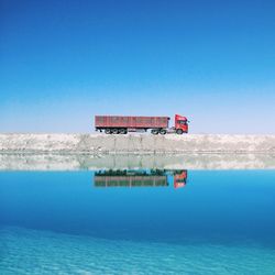 Lifeguard hut on sea against clear blue sky