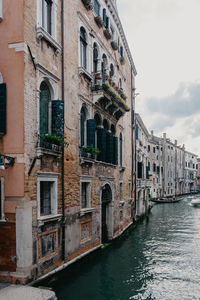 Buildings by canal against sky