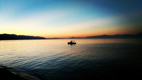 Boats in sea at sunset