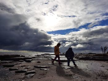 Friends standing on beach against sky