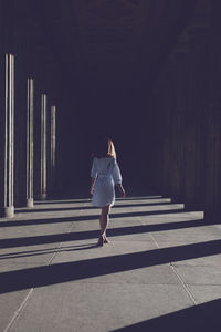 Rear view of woman standing at colonnade