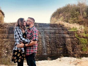 Young couple kissing by waterfall