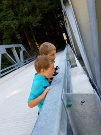 Boys leaning on railing while standing on bridge