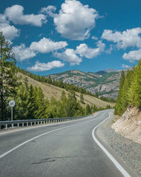 Road leading towards mountains against sky