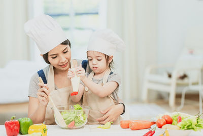 Young woman holding ice cream in kitchen