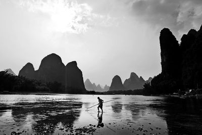 Man with stick walking at beach against sky