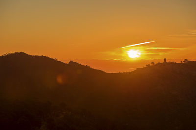 Scenic view of silhouette mountains against orange sky