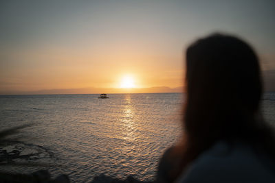 Silhouette woman by sea against sky during sunset