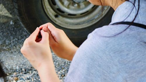 Midsection of woman holding equipment against tire