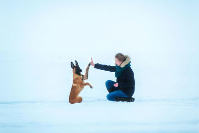 Side view of child on snow against sky