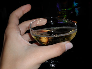 Cropped image of woman holding champagne glass in nightclub