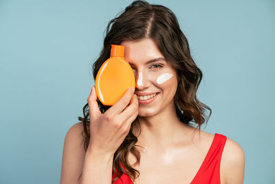 Portrait of a smiling young woman against blue background