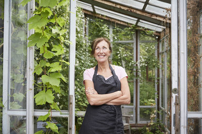 Senior gardener standing arms crossed while looking away at yard