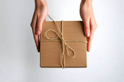 Cropped hand of woman holding gift against white background