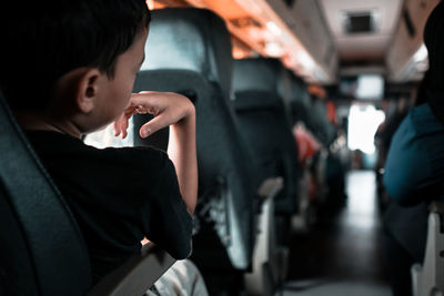 Rear view of boy sitting in bus