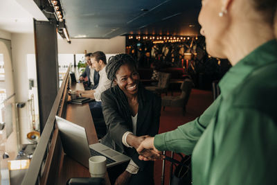 Smiling young businesswoman greeting female colleague in hotel lounge