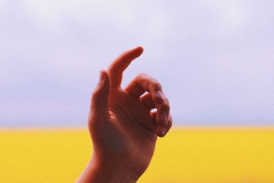 Cropped hand of woman gesturing against wall